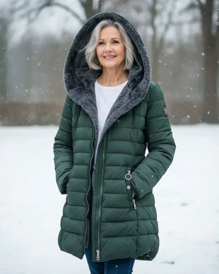 Beatrix hooded long puffer jacket in dark green, worn with hood up in snow