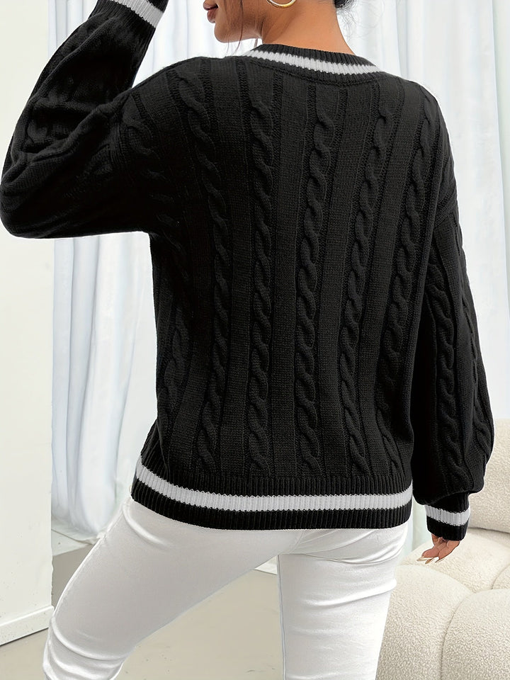 Woman wearing black cable-knit V-neck sweater, styled with white pants and bag