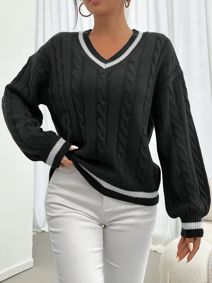 Woman wearing black cable-knit V-neck oversized sweater, holding coffee cup
