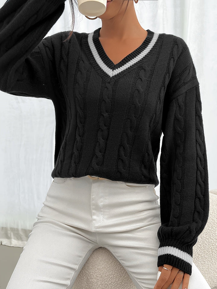 Woman wearing black cable-knit V-neck oversized sweater, holding coffee cup