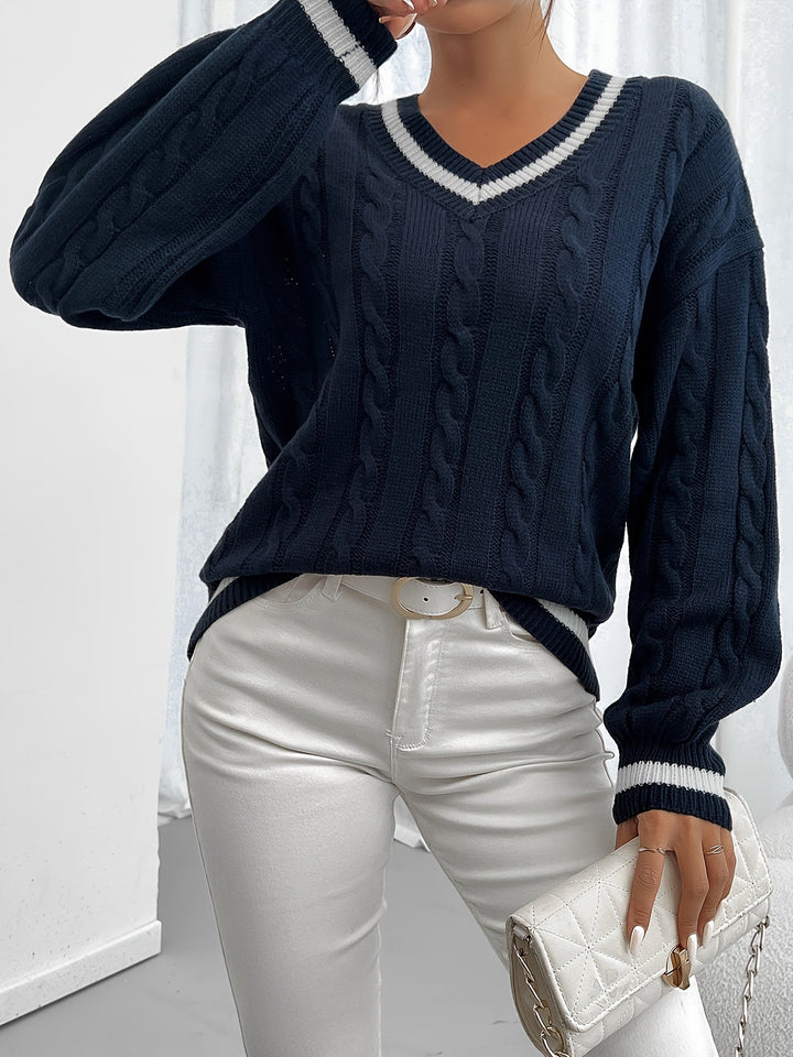 Woman wearing navy cable-knit V-neck oversized sweater, holding coffee cup