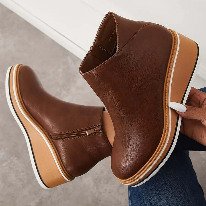 Harlow brown wedge ankle boots held by hand showing sole detail