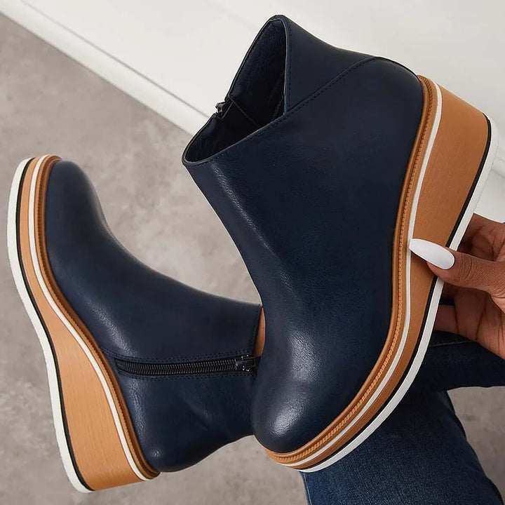 Harlow navy ankle boots held by hand showing wedge sole detail
