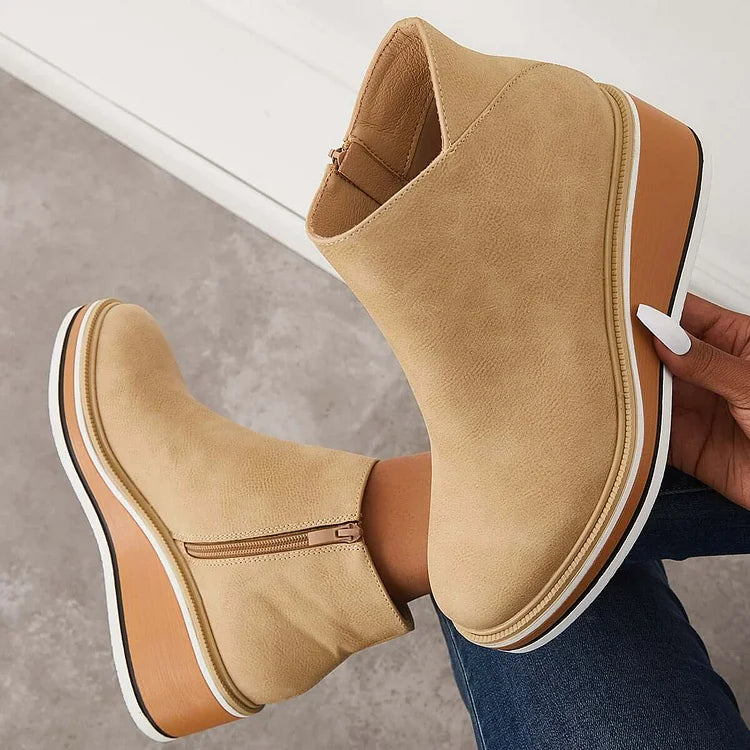 Harlow beige wedge ankle boots held by hand showing sole detail