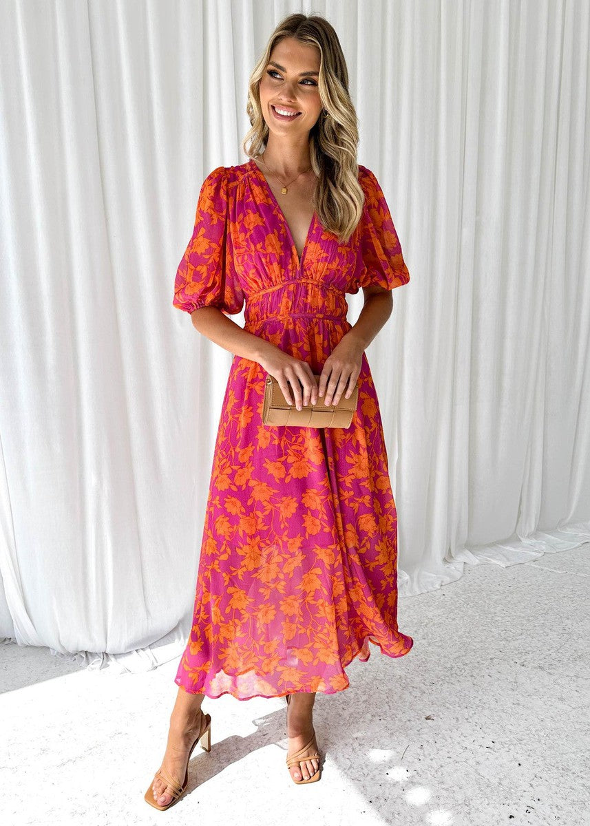 Isa floral maxi dress with puff sleeves, front view holding clutch