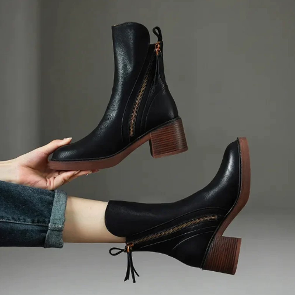 Juniper black leather ankle boots held and worn, showing zip and heel detail