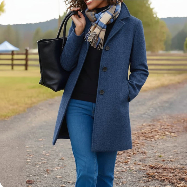 Marielle classic single-breasted mid-length coat in blue, front view with black tote bag