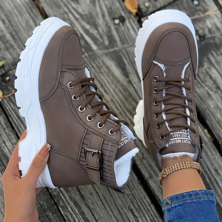 Marissa brown high-top sneaker boots held by hand showing buckle detail