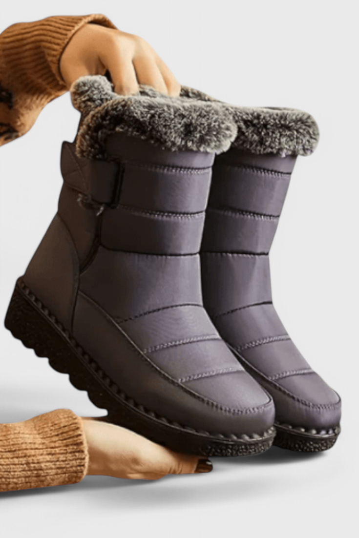 Marlowe waterproof winter boot in gray with faux fur trim, side view held by hand