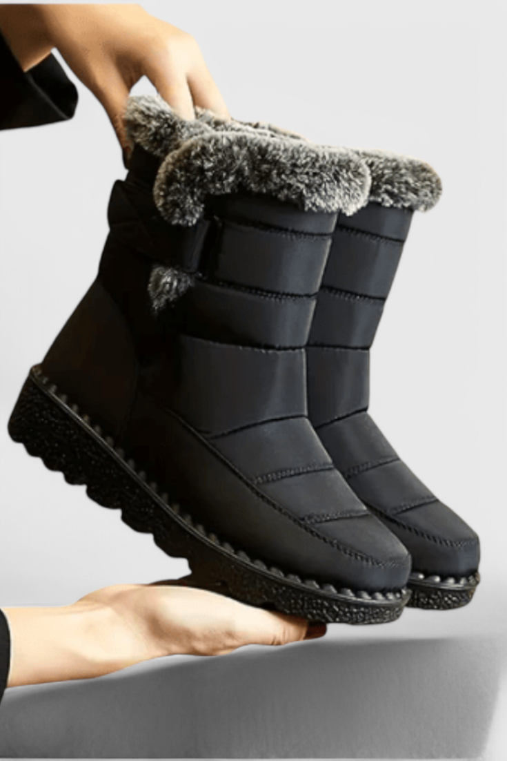 Marlowe waterproof winter boot in black with faux fur trim, side view held by hand