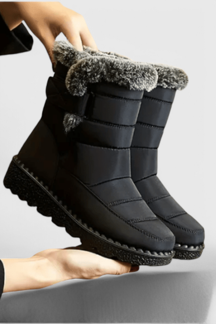 Marlowe waterproof winter boot in black with faux fur trim, side view held by hand
