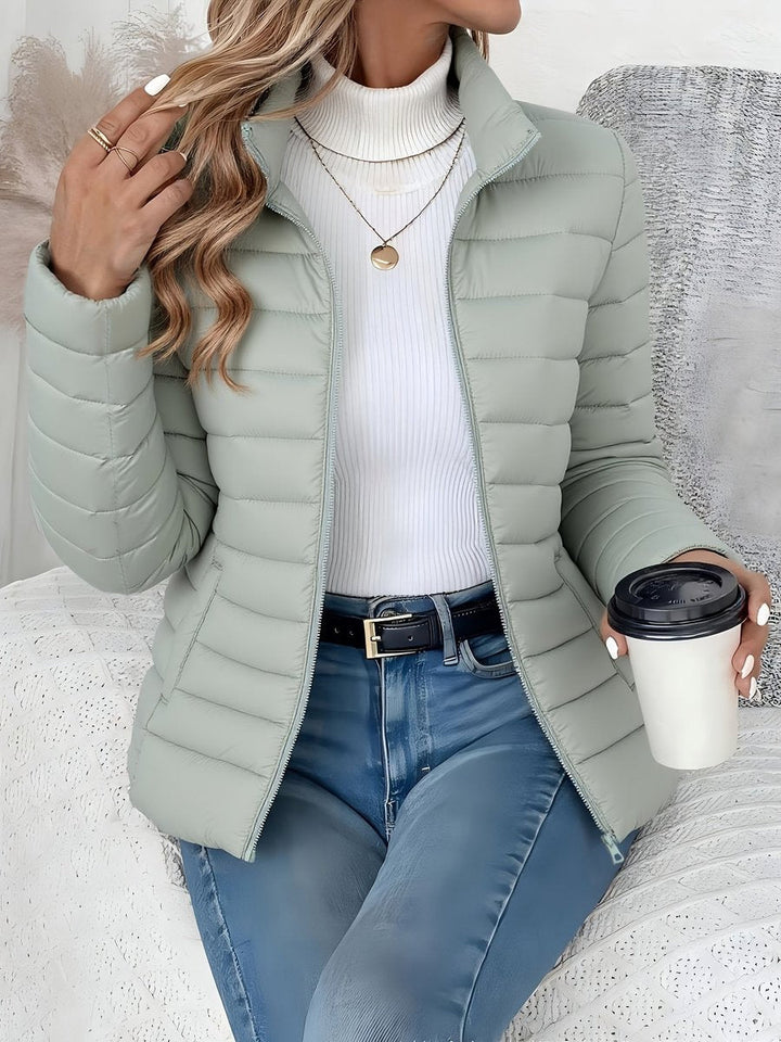 Sienna sage green quilted puffer jacket, front view with hand in hair