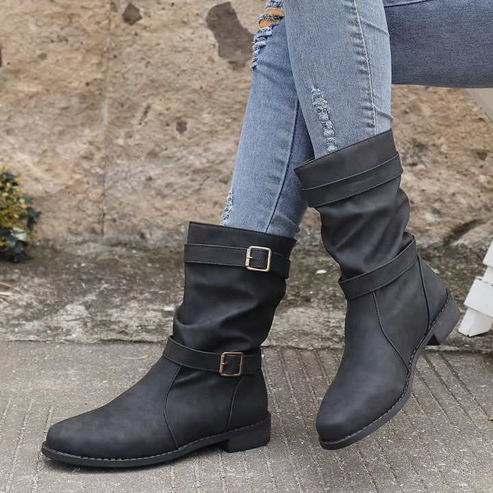 Wilhelmina buckle strap western boots worn while walking, side profile