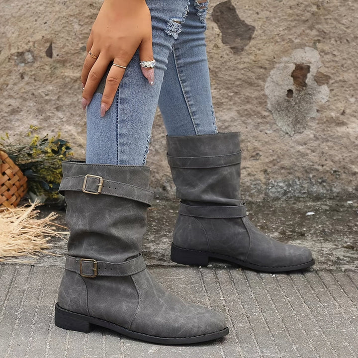 Wilhelmina buckle strap western boots worn while walking, side profile