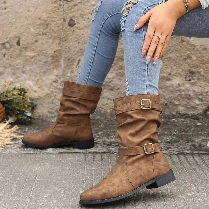 Wilhelmina buckle strap western boots worn while walking, side profile