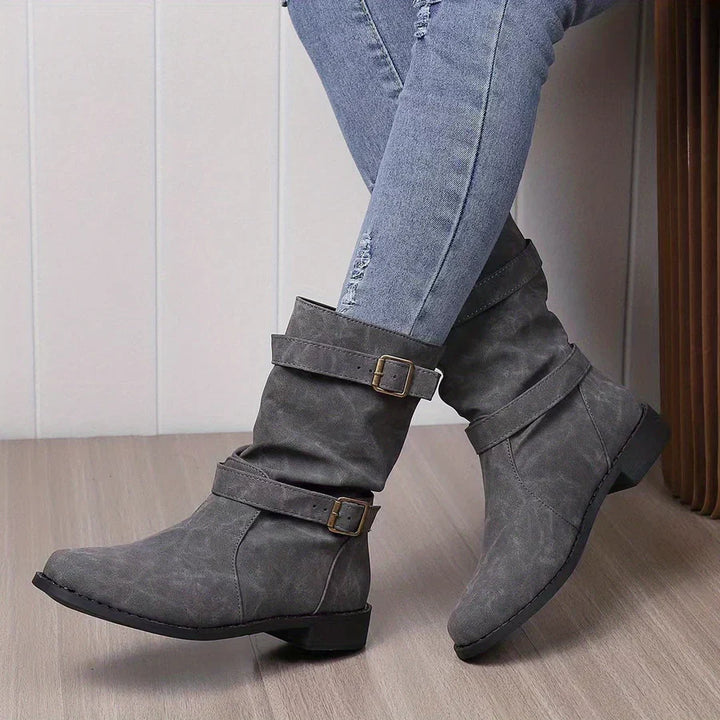 Wilhelmina buckle strap western boots worn while walking, side profile