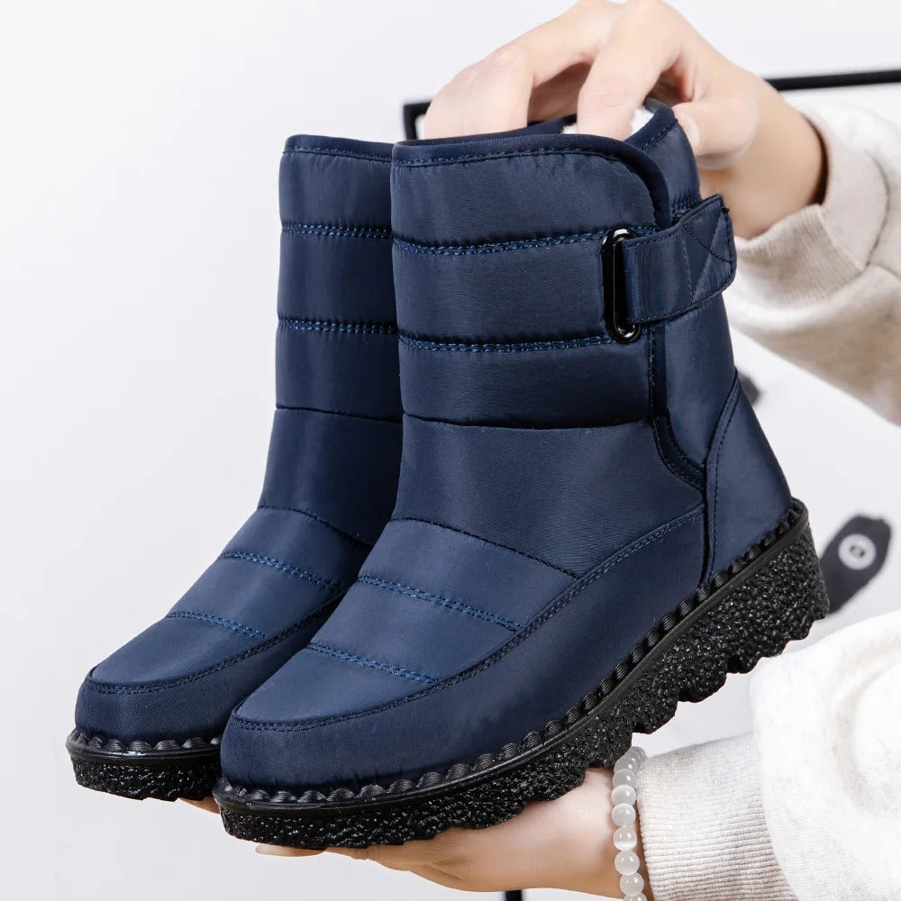 Winifred waterproof mid-calf snow boots in navy blue, held up by hand, side view