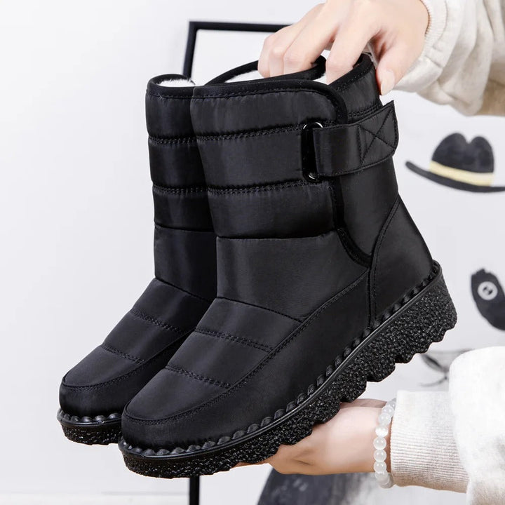 Winifred waterproof mid-calf snow boots in black, held up by hand, side view