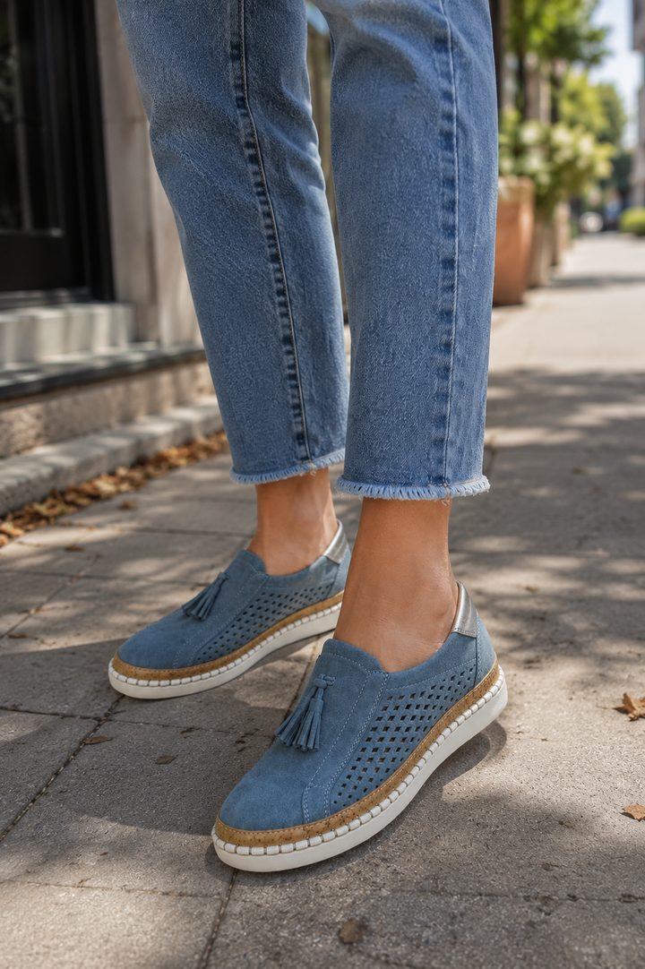 Isadora perforated tassel slip-on loafers in blue, side view on model with jeans