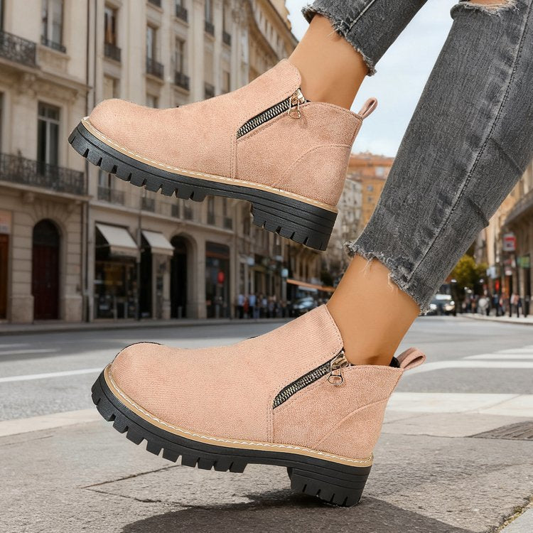 Pink ankle boots with pull tab worn by model stepping off curb