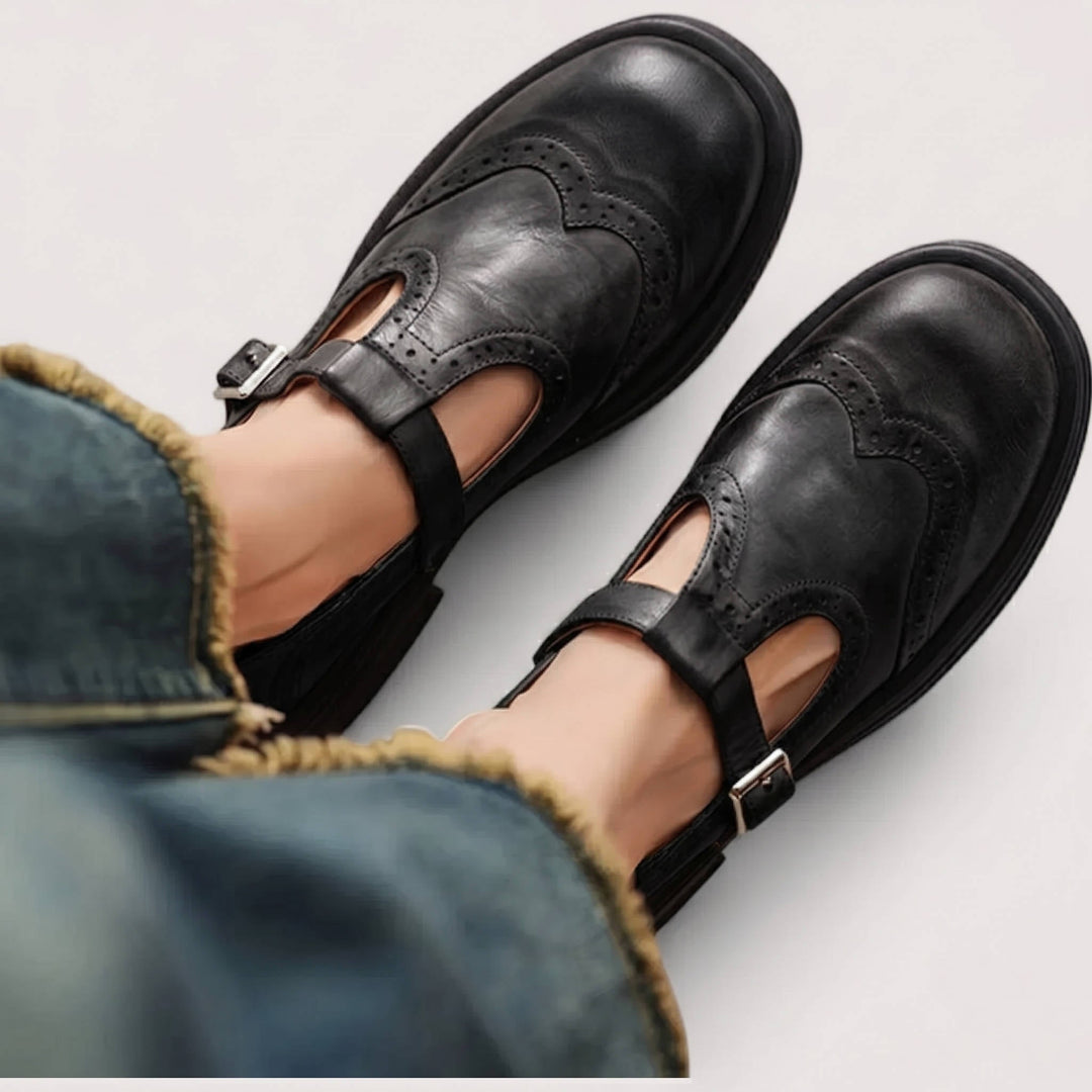 Thea wingtip Mary Jane shoes in black, top-down view on model