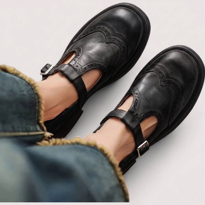 Thea wingtip Mary Jane shoes in black, top-down view on model